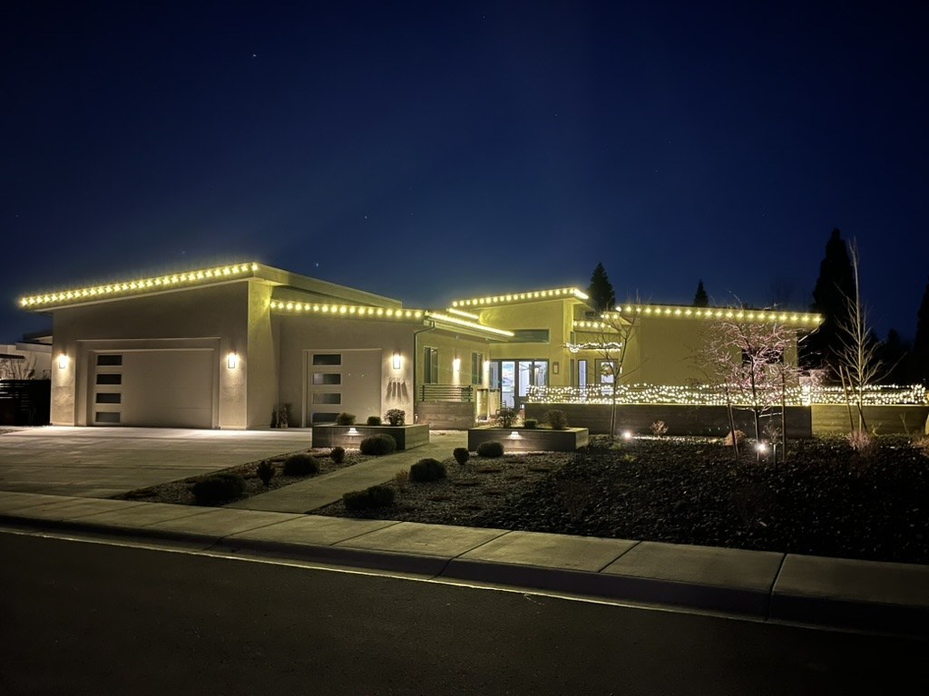 Modern home outlined in warm white C9 Christmas lights at dusk